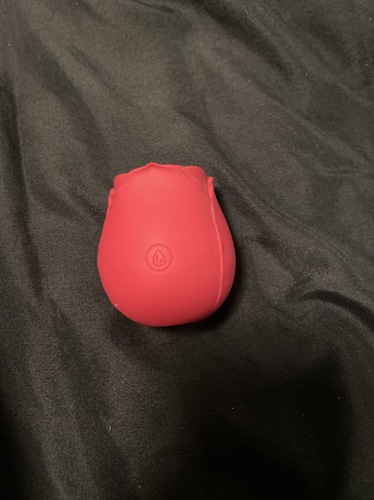 Red rose toy on black fabric with its single power button visible