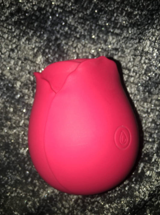 Close-up of a pink-red rose toy on dark glitter fabric