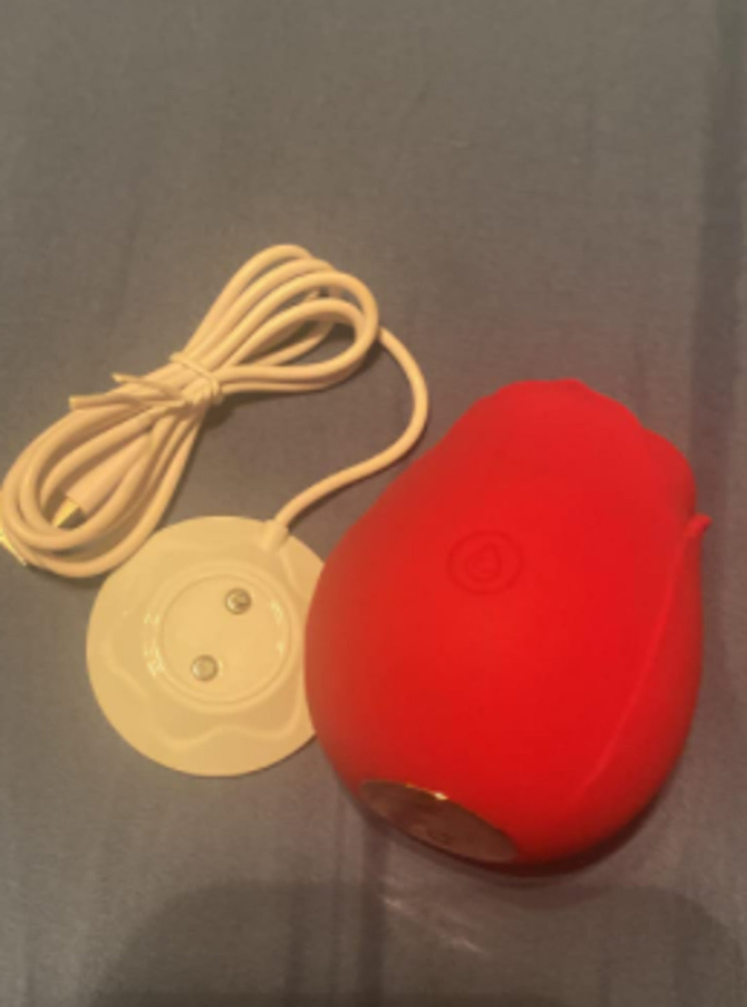 Red rose toy next to its white magnetic charging dock and cable