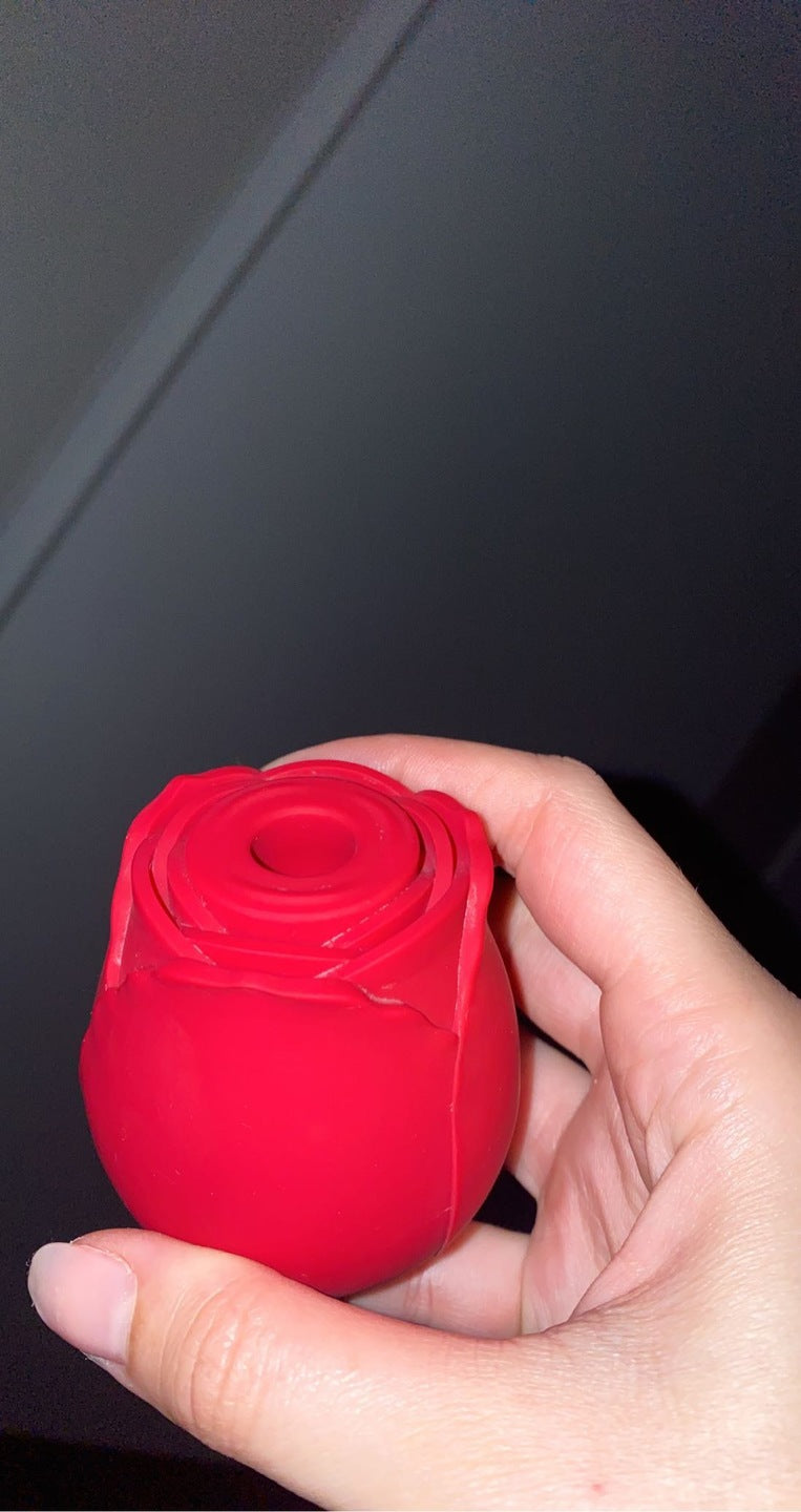 Red rose toy held in a hand, showing the petal layers and suction opening