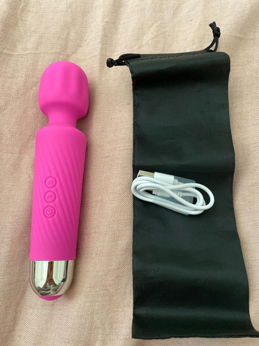 Hot pink magic wand vibrator lying beside a black drawstring storage pouch and a white USB charging cable.